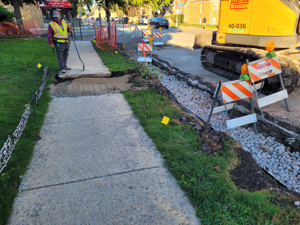 Crew preparing the excavated curb line beside the sidewalk along 16th Street.