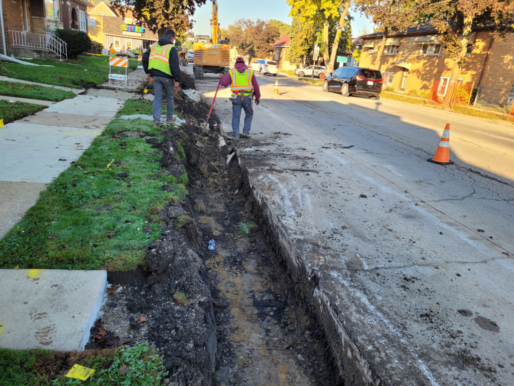 Workers preparing a trench for curb and gutter along 16th Street.